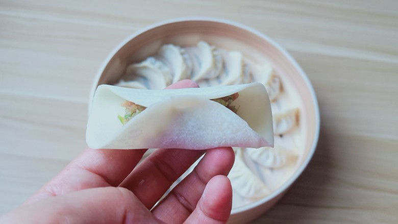 猪肉芹菜蒸饺,饺子皮半圈沾一点点水,有利于粘合。饺子馅放一点,先把饺子皮中间捏一下。