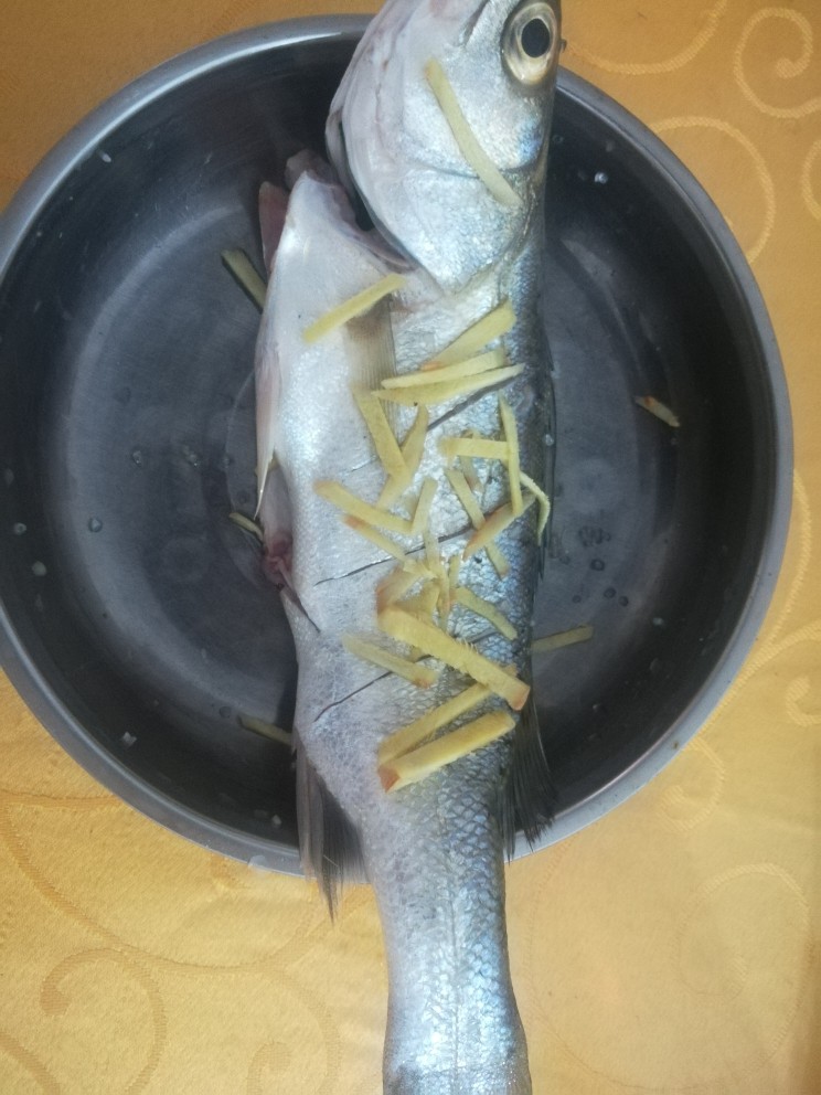 清蒸鲈鱼,将葱段和姜片塞进鱼肚，姜丝撒鱼身，鱼两面都抹上<a style='color:red;display:inline-block;' href='/shicai/ 718'>料酒</a>和盐，腌制半小时后入锅蒸十分钟