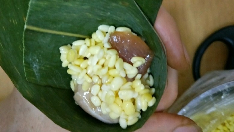 彩色三角粽,然后放半勺绿豆和一块五花肉,肉的上面再放半勺绿豆。