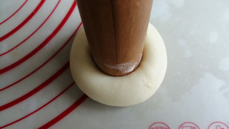 蓝莓酥粒面包,擀面棍的一头沾点面粉,在面团中间用力压一下