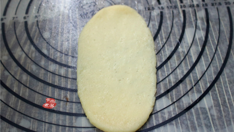 蛋黄酥,将松弛好的面团用手掌摁扁,再用擀面杖擀成椭圆形。