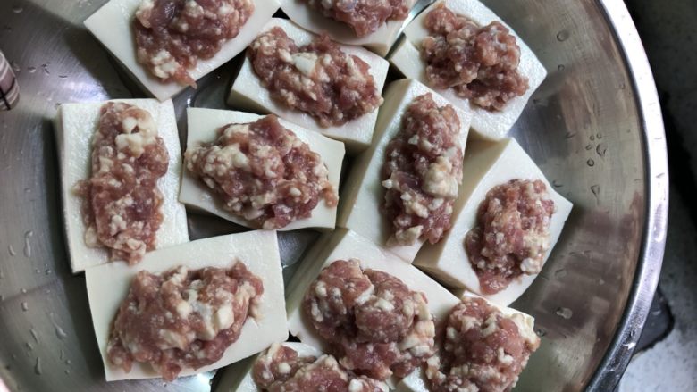 瘦肉让豆腐,将搅拌好的肉分进豆腐坑里,然后放进电饭煲跟饭一起开锅