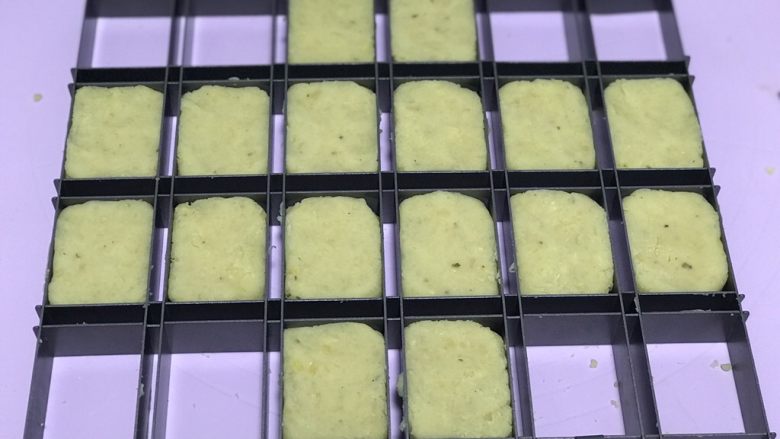 奶香绿豆糕,炒好晾凉后及绿豆泥分成41克左右一份,放入模具中,如果放馅料的话就按扁加入适量红豆馅滚圆再继续操作。