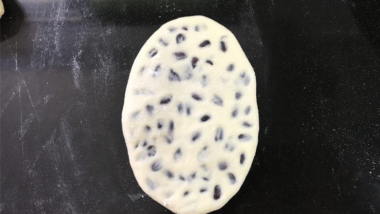 玉米面蜜豆卷,把包入蜜豆的面团重新用擀面杖轻轻擀开。