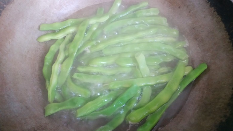 土豆豆角炒五花肉,锅中放入适量清水烧开,放入四季豆烧开四五分钟