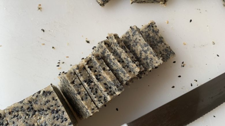 黑白芝麻酥块,冷冻好的面团取出,切成0.8cm左右的片,摆入烤盘。