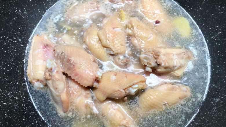 蒜香蚝油鸡翅,把鸡翅放入锅里,放入姜片,倒入适量水,大火把水煮开,把鸡翅煮出血沫,煮出血沫以后,用清水冲洗干净沥干水待用。