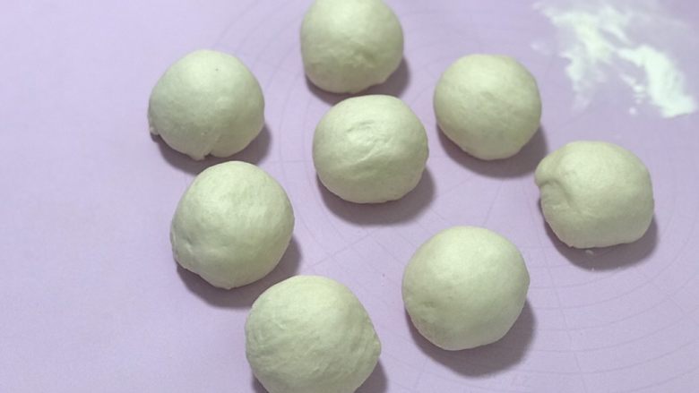 奶香蜜豆面包卷,发好的面团排气后分成55克左右的几个小面团,整理一下盖上保鲜膜松弛20分钟左右。