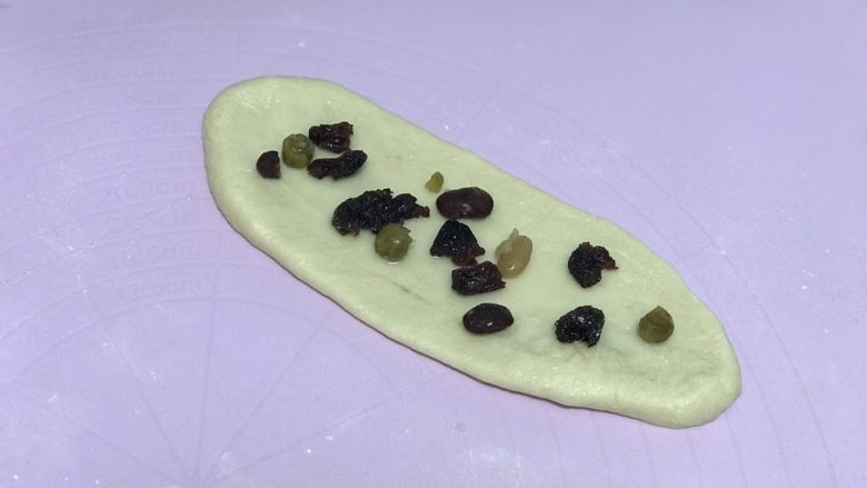 奶香蜜豆面包卷,松弛好的面团再次排气,擀成长条状抹上一层炼乳撒上蜜豆。