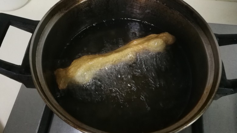 小油条,锅中油热,将面条两头用手捏着轻轻拉长,放入油锅炸