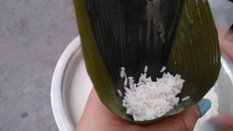 花生、蜜枣、葡萄干粽子,2片粽叶叠在一起,从中间叠成漏斗状,放入少许糯米。