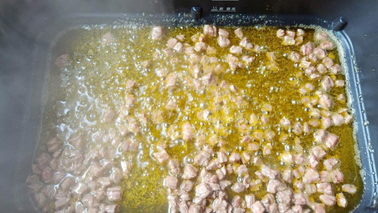 万能酱料【香辣牛肉酱】,锅里多加一点菜籽油【用菜籽油炒出来的牛肉酱特别的油光红亮,味道更好】油温五成热加牛肉丁翻炒至变色先盛盘备用。