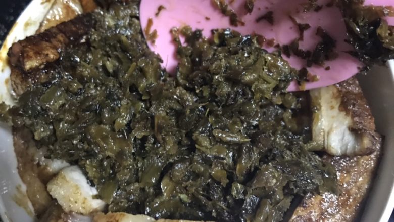 梅菜扣肉,肉片中放入姜片,大葱段,八角,香叶。放入炒好的芽菜压一压。