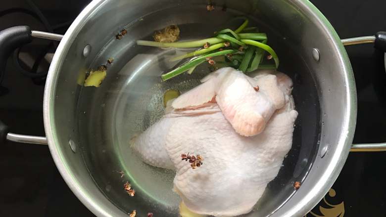 口水鸡,锅中倒入适量水,放入葱结,花椒和老姜,把鸡一起放入。