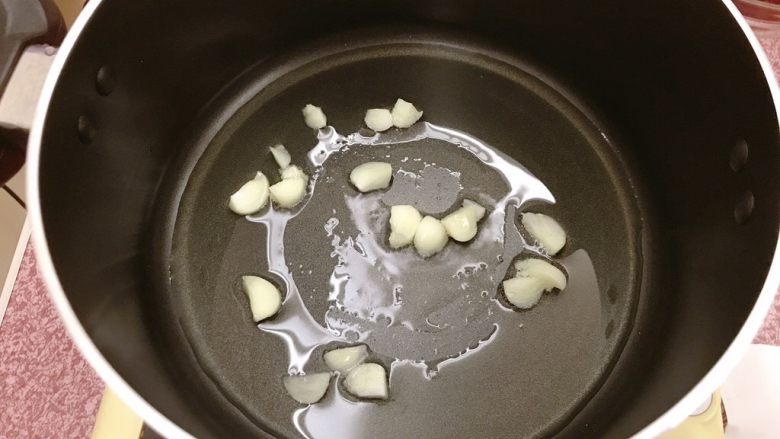 年糕蟹煲,锅内热油,放入蒜片,炒出香味。