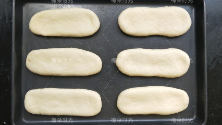 葱香肠仔包,依次擀好六个。放在烤盘里。进行第二次发酵。我还是放进烤箱里,底部放一杯温热水,面团表面和烤箱四周我喷了一些水雾,来保持湿度。