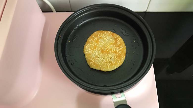 山药苹果小饼,煎锅中刷上一层油,把沾了芝麻的糯米饼放入锅中,一面煎好后翻面煎另一面,煎至两面都呈金黄色后即可。