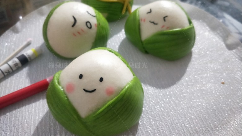 花样馒头——粽子馒头,蒸熟后,用黑色烘培笔(就是可食用色素笔)在空白处给粽子画上各种表情。用红色笔画出腮红。