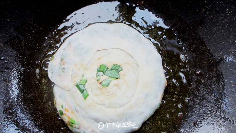 家常韭菜饼,平底锅涂一层油,油温热后转小火放入韭菜饼坯子,煎一会就翻转过来煎另一面,煎的过程要两面不断翻转避免煎焦。煎到两面金黄即可。由于面团是卷的,建议多煎一会让卷在里面的面也熟透。