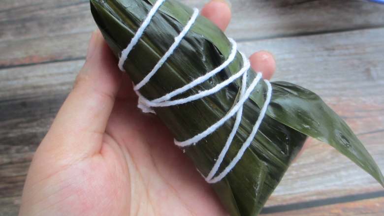 五花肉棕,把粽子盖上,用大拇指按住,包好后用绳捆起来