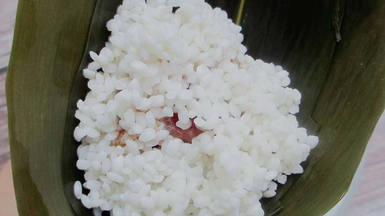 五花肉棕,再放入一勺米,用勺子压实