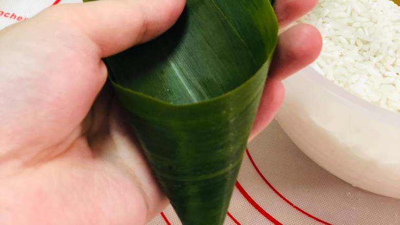 紫薯粽子&小米糯粽 ,取粽叶,如果粽叶比较小,就用两张一起,重叠但稍微分开一些,卷成一个圆锥形。