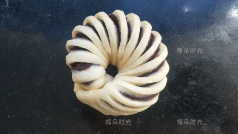豆沙面包卷,然后卷成一个圆形的圈。依次做好所有的,放在面包托里面,没有也可以直接放在烤盘上。开始发酵。