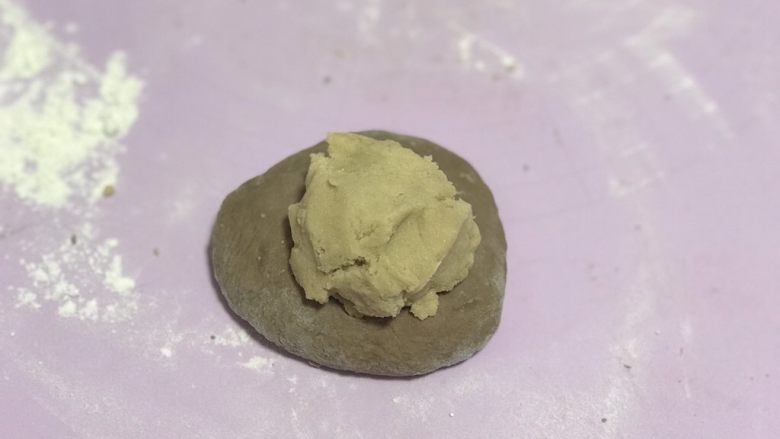 可可奶酥软欧,松弛完毕后,奶酥馅也分成6份,把面团按扁,取一份奶酥馅放入面团中。