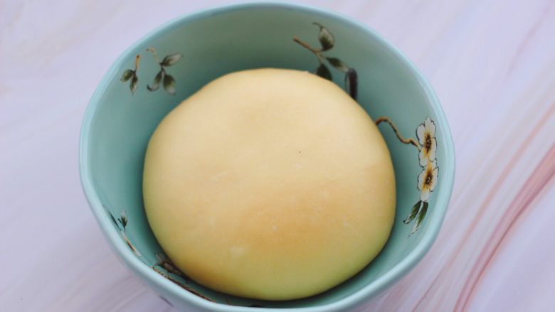 胶东喜饼,和好的面团揉圆后,放入一个大一点的容器里,盖上保鲜膜开始醒发。