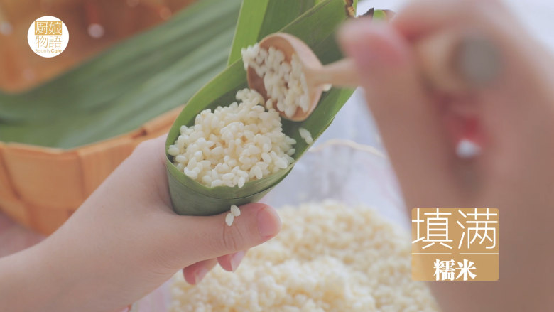 奶奶的碱水粽「厨娘物语」,两片粽叶卷成漏斗状填满糯米,将粽叶向下折叠,沿边卷起。