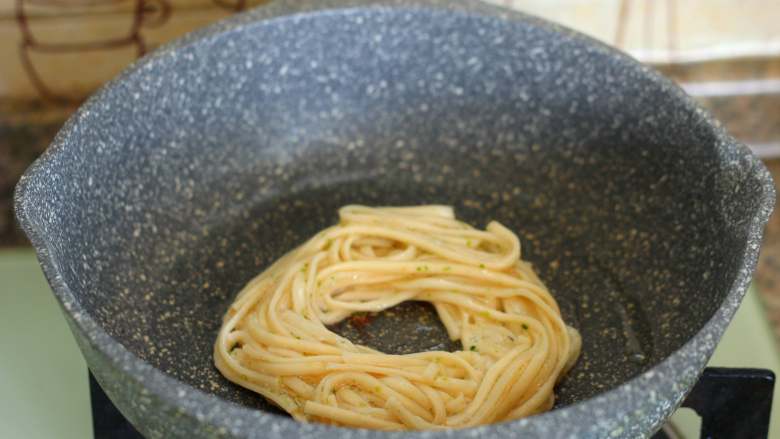 鸟巢煎蛋,平底锅中小火烧热,倒入适量的食用油,把拌好的面条放到锅里,绕成一个圆形。
