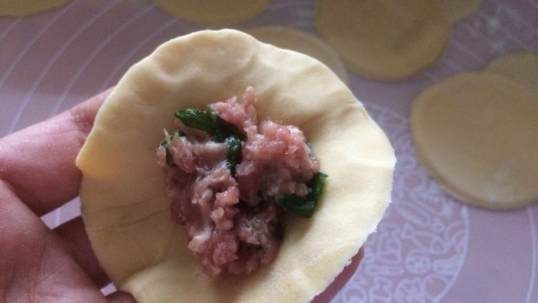 萌萌哒小猪(主)饺(角),醒好的面团 擀成薄片,用圆形模具压出饺子皮,然后取一张饺子皮,中间放一点饺子馅;