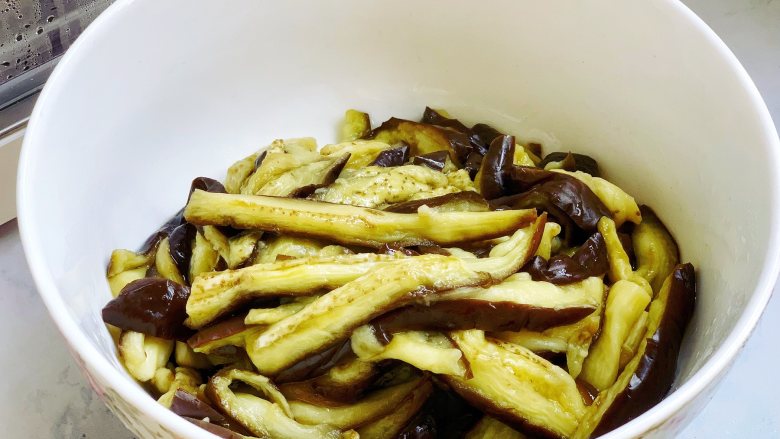 凉拌手撕茄子,茄子取出放凉,然后抓干一点水分,用手撕成长条状,放入碗里备用。夏天可以把茄条放冰箱冷藏一下再凉拌,吃起来冰凉冰凉的,非常爽。