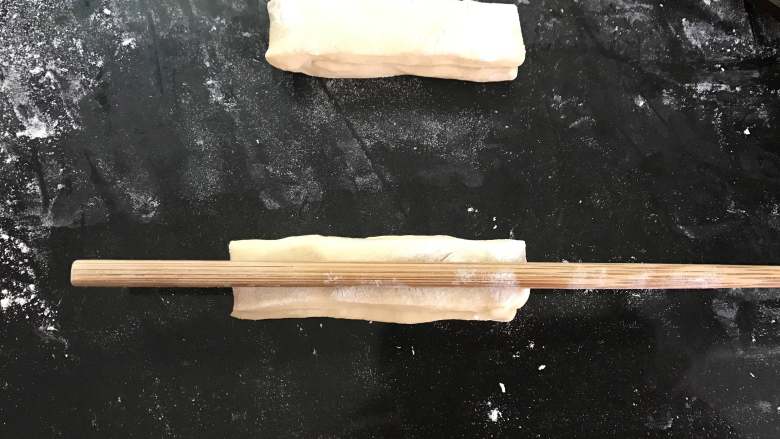 自制油条,把两个面条叠起来,用筷子在中间压出一条纹路。