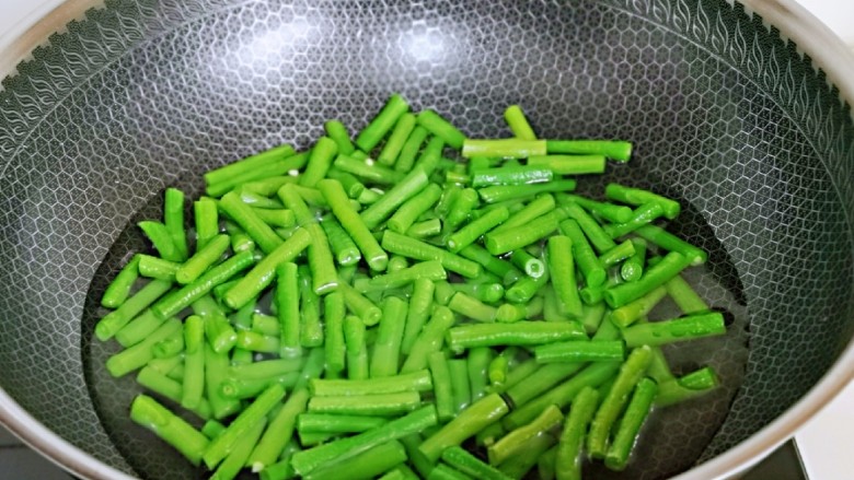 虾仁炒豇豆,锅中加入水烧开,下豇豆,滴入食用油,大火焯水2分钟,捞出过冷水。