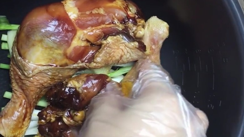 电饭煲焖鸡腿,电饭煲底部放上葱段,姜片,倒入一小勺食用油,鸡皮朝下放入鸡腿