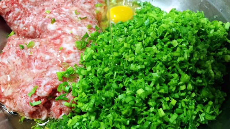 猪肉蒜苗水饺,猪肉馅、蒜苗碎放入盆中,打入一个<a style='color:red;display:inline-block;' href='/shicai/ 9'>鸡蛋</a>,倒入玉米油