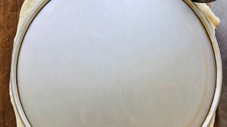 奥尔良鸡肉薄底披萨,面团30分钟发酵好以后,用擀面杖擀开,一定要轻柔,切记大力避免擀破了。然后我用8寸蛋糕底托裁出一个圆形。如果有披萨烤盘可以直接用。