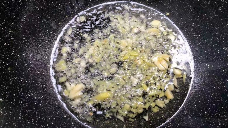 胡萝卜芦笋炒鱿鱼,热锅放入适量油,烧至七成热,放入姜蒜末煸出香味。