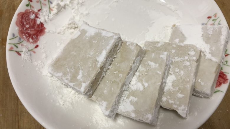 香煎鸡蛋豆腐,将切好的豆腐块在干淀粉中滚一下,表面均匀粘上淀粉。