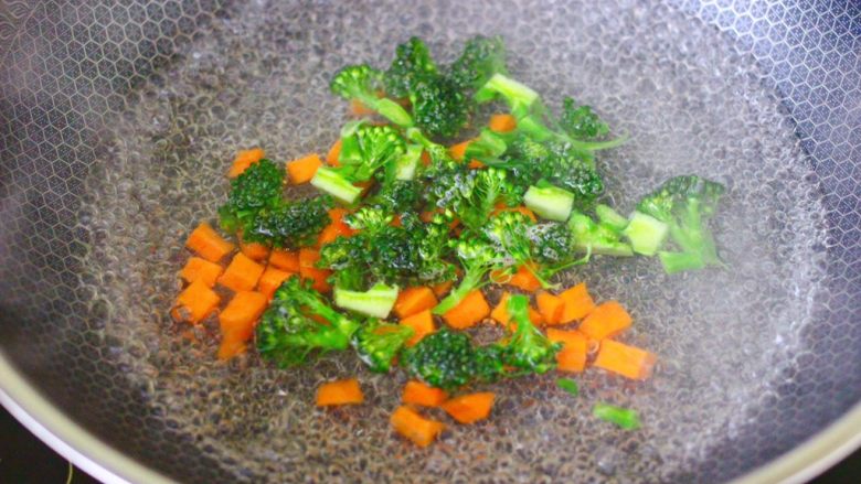 西兰花猪肝粥(宝宝辅食),锅中倒入适量的清水烧开后,加入少许盐和几滴食用油,把胡萝卜和西兰花进行焯水1分钟后,捞出沥干水分备用。