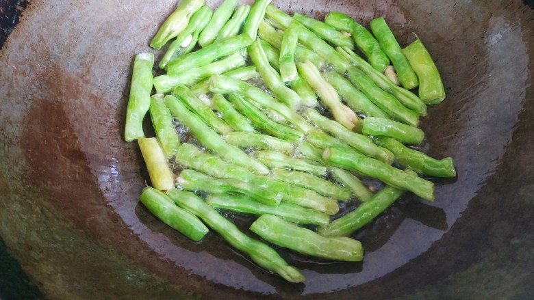 四季豆烧茄子,锅中放入适量<a style='color:red;display:inline-block;' href='/shicai/ 857'>植物油</a>,放入四季豆翻炒至出现虎皮