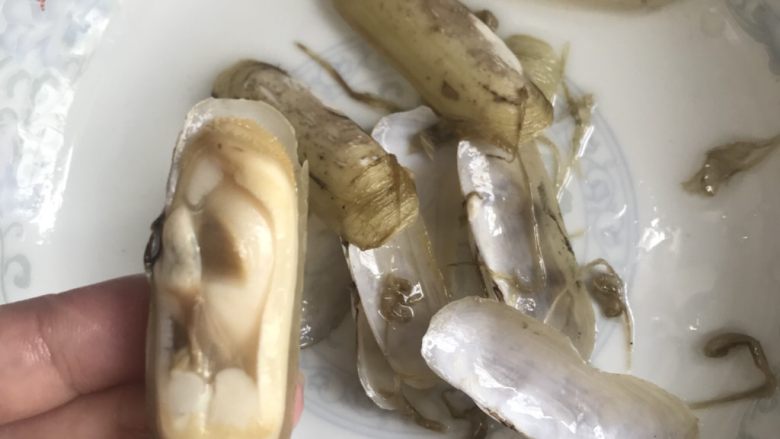 油淋竹蛏,用剪刀剪掉一半蛏壳,清理蛏肉旁边的黑线。