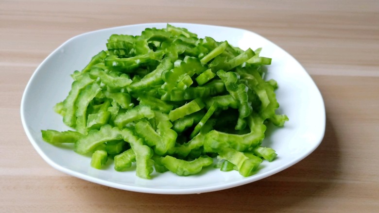 苦瓜炒牛肉,苦瓜对半切开,挖瓤,苦味的瓤尽量都去除干净,苦瓜切薄片。