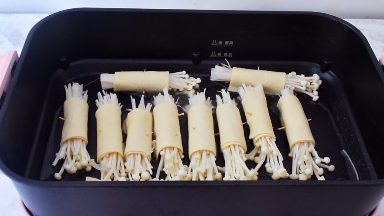 豆皮金针菇卷,锅中倒入少许的食用油烧热,放入豆皮金针菇卷