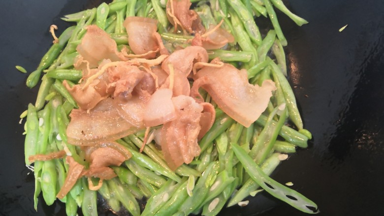 四季豆炒咸肉,把咸肉倒入,翻炒均匀