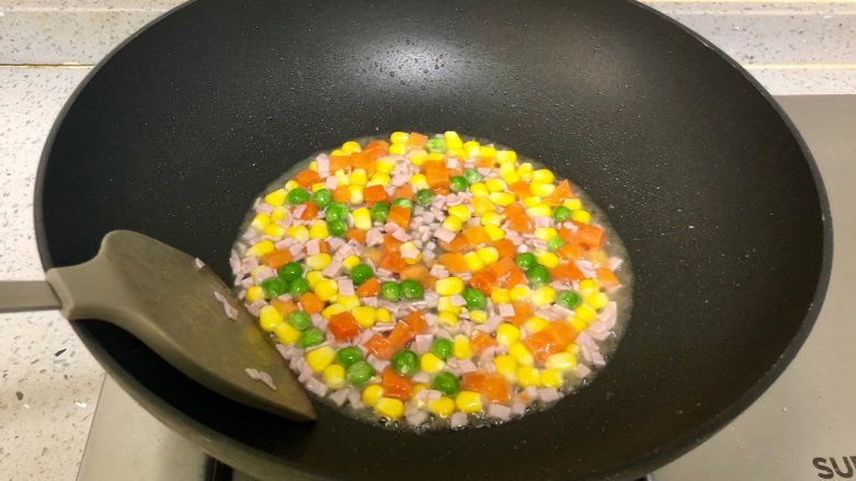 小黄人蛋包饭,下入解冻好的什锦蔬菜粒翻炒;