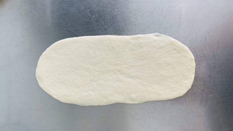 汤种酸奶吐司🍞,取一个静止好的面团,轻柔地擀成长条。用手轻捏排除边缘的小气泡。