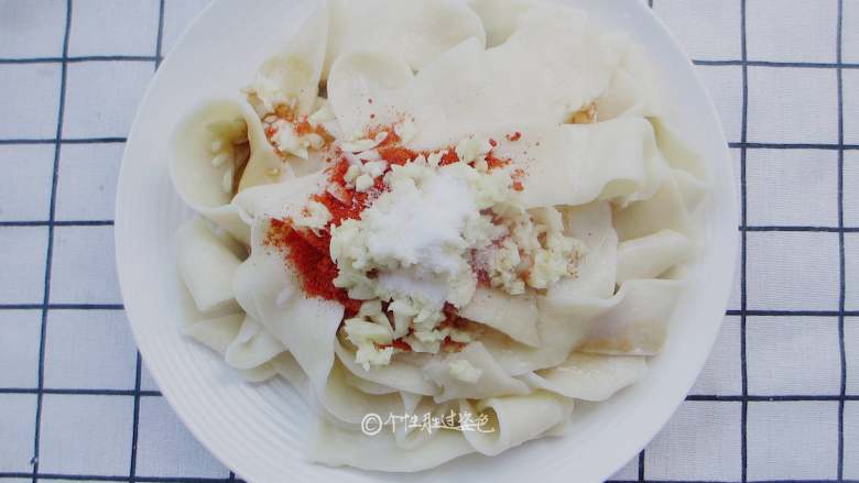 大碗宽面,盖上面条,撒上蒜末、辣椒粉、花椒粉、盐、5克醋、5克味极鲜