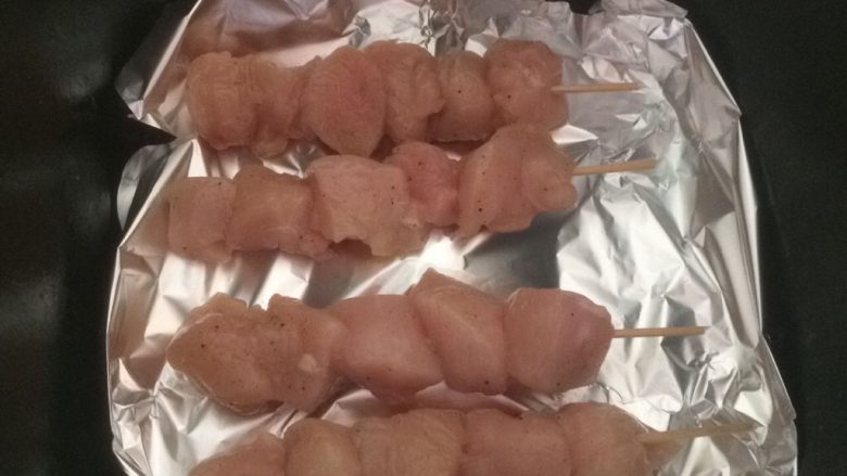 孜然味烤鸡肉串,空气炸锅铺上锡纸,摆入鸡肉串;